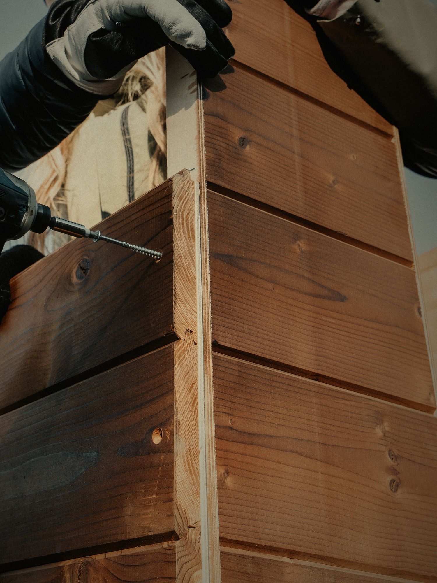 Hands fitting the corner of a Moodem thermowood wall with a cordless drill